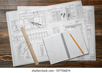 Open blueprints on wooden table background with a pencil, a ruler and compasses lying beside. Engineering and design. Construction projects. Planning.