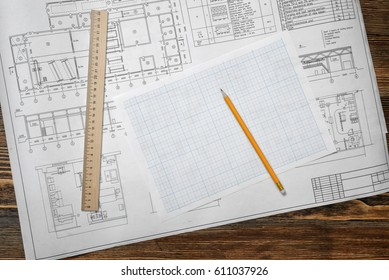 Open blueprints on wooden table background with a pencil and a ruler lying beside. Engineering and design. Construction projects. Planning.