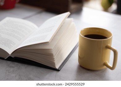 Open book with black cover and yellow cup of coffee on the table. Close up view. - Powered by Shutterstock