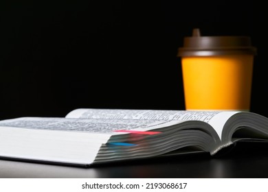 Open book with bookmarks and a cup of coffee on a dark background