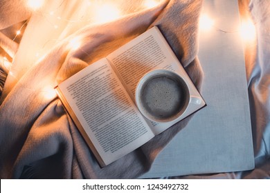 Open Book With Cup Of Coffee In Bed At Night. Top View. 