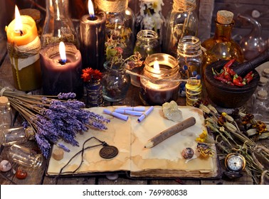 Open book with healing herbs, lavender flowers, candles, potion bottles and magic objects. Occult, esoteric, divination and wicca concept. Mystic, old apothecary and vintage background