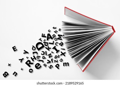 Open book with letters on white background, top view. Dyslexia concept