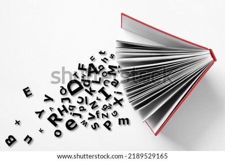 Open book with letters on white background, top view. Dyslexia concept