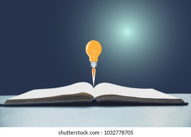 Open Book With Light Bulb Launch. Book Open On Desk.