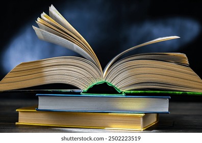An open book lying on a stack of other books.