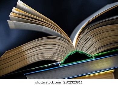 An open book lying on a stack of other books.