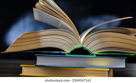 An open book lying on a stack of other books.