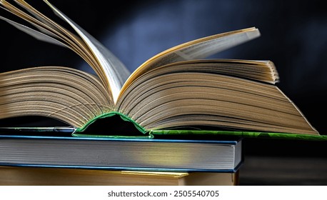 An open book lying on a stack of other books.