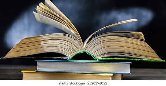An open book lying on a stack of other books.