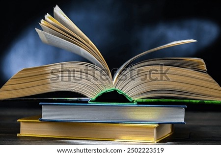 An open book lying on a stack of other books.