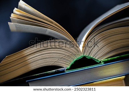 An open book lying on a stack of other books.