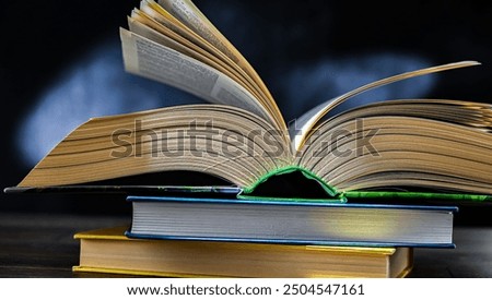 An open book lying on a stack of other books.