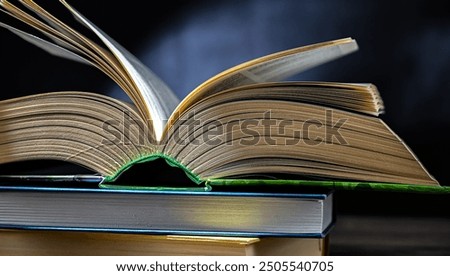An open book lying on a stack of other books.