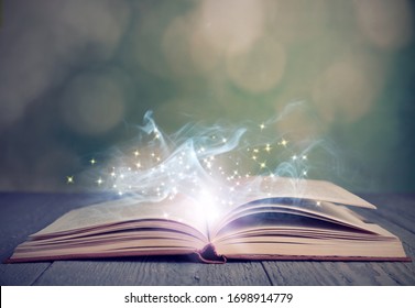 Open book with magic glowing on wooden table. Fairy tale