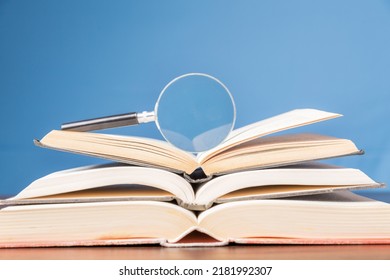 open book with magnifying glass on wooden desk in information library of school or university, concept for education,reading , study, copy space and blue background. - Powered by Shutterstock