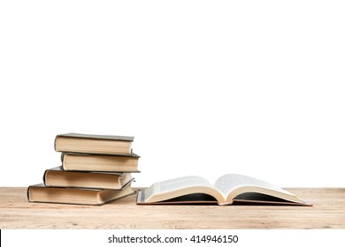 Open Book Near The Pile Of Books Lying On A Wooden Table Isolated On White Background