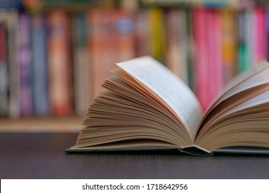 An open book on the background of a bookshelf with books. Library - Shutterstock ID 1718642956