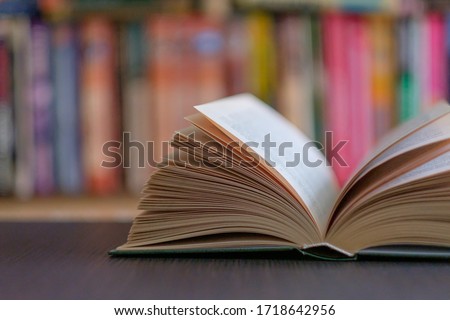 An open book on the background of a bookshelf with books. Library