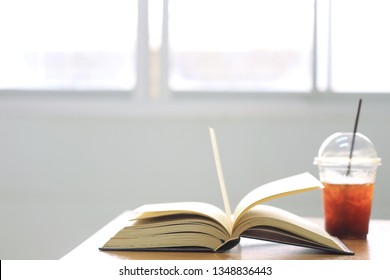 Open Book On The Office Desk Iced Coffee Mug As Background Selective Focus And Shallow Depth Of Field