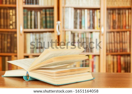 The open book is on the table in the background of the library.