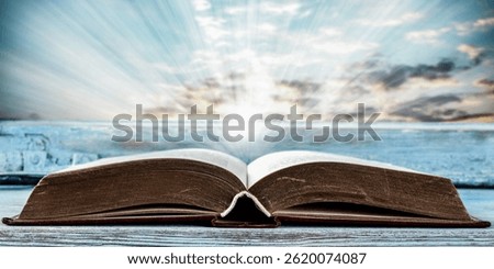 Open book on windowsill with dramatic sunset sky through old rustic window. Dreamy and nostalgic scene evoking calm, imagination and the beauty of quiet moments. Copy space for text and product.
