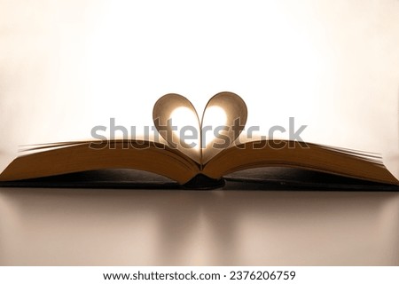Open book and pages folded to form a heart, on a white background. Passion for reading.
