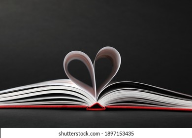 Open Book With Pages Folded In Heart On Black Background