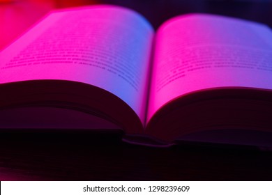 Open Book With Pink Neon Light Over Dark Background