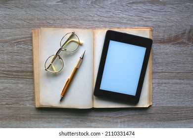 Open Book, Reading Glasses, Golden Mechanical Pencil And E-reader Device On The Table. Top View.