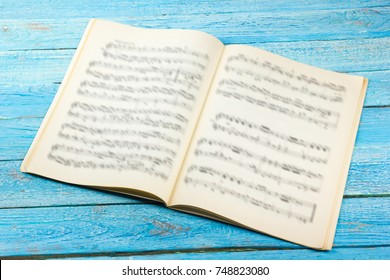 Open Book, Sheet Music. Musical Notes On A White Wooden Table.