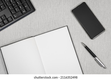 Open book with a smatphone and a computer keyboard on a desk. White pages for inscriptions.	 - Powered by Shutterstock