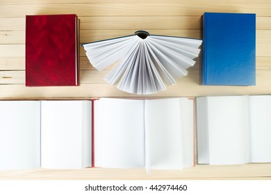 Open book, stack of hardback books on wooden table. Back to school. Copy space.