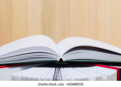 Open book, stack of hardback books on wooden table. Back to school. Copy space.