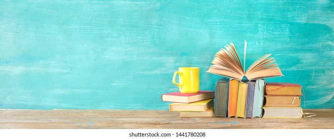 Open Book And Stack Of Multicolored Hardback Books With A Cup Of Coffee, Reading Education, Literature, Panoramic, Good Copy Space