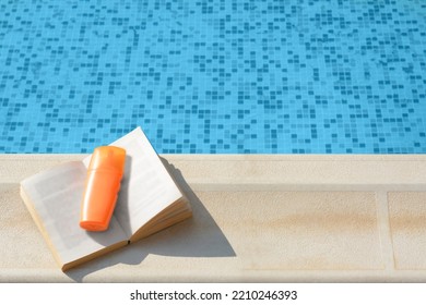 Open Book And Sunscreen On Swimming Pool Edge, Above View. Space For Text