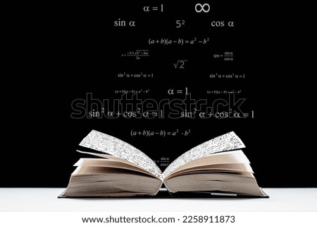 An open book, a textbook lies on the table. Metematic signs and formulas on a black background. The study of mathematics, algebra, geometry.