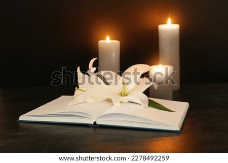 Open book, white lily flowers and burning candles on dark background [[stock_photo]] © 