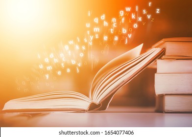Open books have floating English letters on wood table. And blurred bookshelf background in the library. Back to school concept and 
education background.