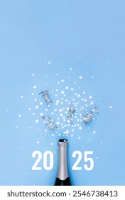 Open bottle of champagne on blue background decorated with silver star confetti and numbers 2025. New Year celebration or party. Selective focus, place for text