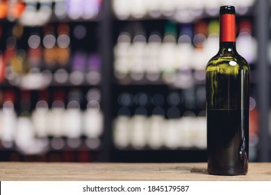 Open Bottle Of Red Wine On Blurry Dark Background Interior In Restaurant.