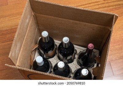 Open Box Of A Half-dozen Bottles Of Wine For Home Delivery Sitting On Wooden Floor