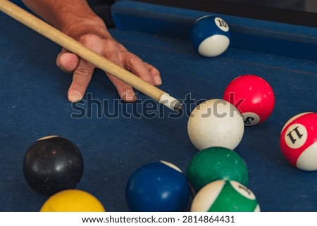Open bridge hand pose aiming cue stick closely at white cue billiard balls, capturing snooker play focus, sport tactic and mindful casual recreation for social game and relaxed leisure time indoors