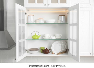 Open cabinet with different clean dishware in kitchen