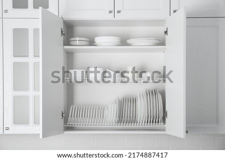 Open cabinet with different clean plates and bowls in kitchen