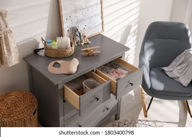 Open Cabinet Drawers With Clothes And Different Items In Child Room