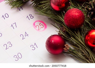 Open calendar of 2022 with a mark on the date of December 25. A branch of Christmas tree with toy balls and cones. Atmosphere of the holiday. Christmas content. Selective focus - Powered by Shutterstock