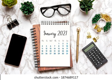 Open Calendar January 2021, glasses, cup of coffee, pen, smartphone, succulents on marble table Top view Flat lay Education, goals, resolutions, plan, small owner business concept Home workplace