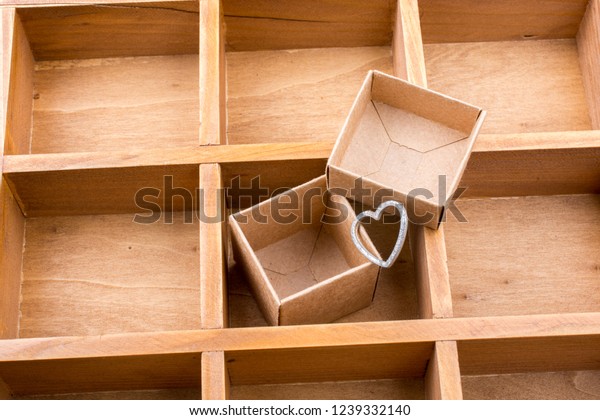 Open cardboard box inside a wooden box with
compartments and a heart