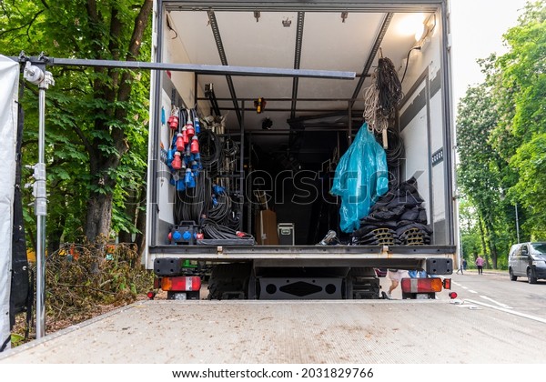 Open cargo box of filming movie set production\
equipment transport truck van vehicle with many electrical cables\
wire, rack and sockets on city streey outdoors. Cinema or\
television supply rental\
car